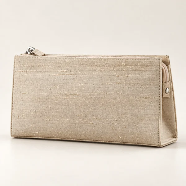 En aflang beige taske med struktur, placeret vandret på et lyst underlag mod en neutral baggrund.